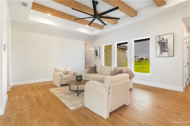 living room with light wood-type flooring, ceiling fan, a raised ceiling, baseboards, and visible vents