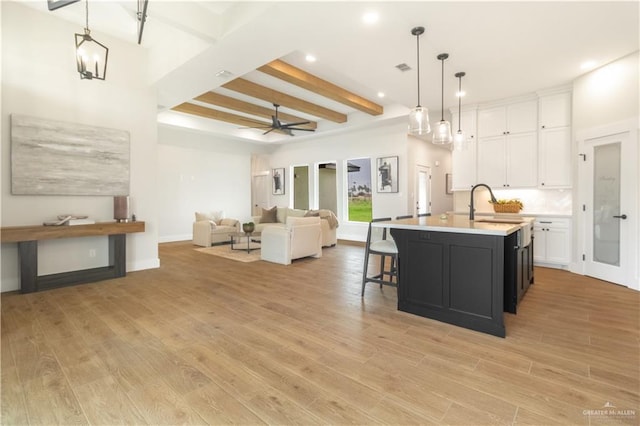 kitchen with beam ceiling, a sink, recessed lighting, white cabinetry, and light countertops