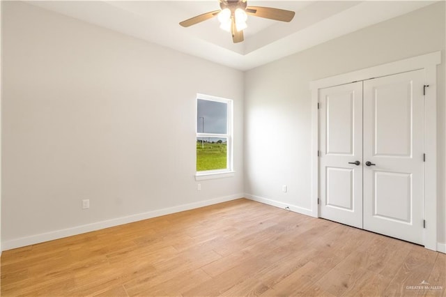unfurnished bedroom featuring ceiling fan, baseboards, a closet, and light wood-type flooring
