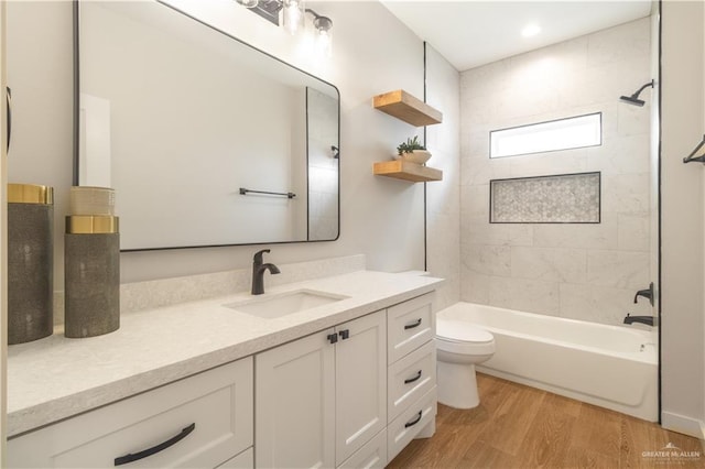 bathroom featuring wood finished floors, toilet, vanity, and shower / washtub combination