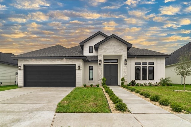 prairie-style house with a shingled roof, a front lawn, concrete driveway, an attached garage, and stone siding