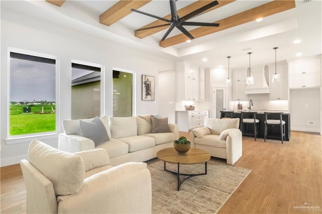living room featuring a ceiling fan, light wood-type flooring, a raised ceiling, beam ceiling, and recessed lighting