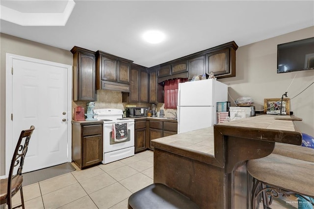 115 W Albatross Ave, Pharr, TX 78577 - kitchen with dark brown cabinetry, white appliances, tile counters, backsplash, and light tile patterned floors