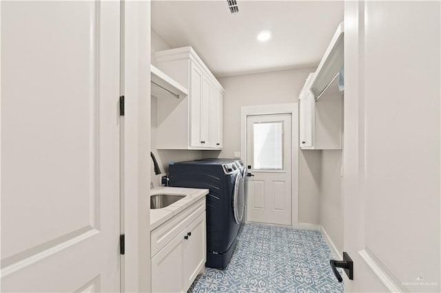 clothes washing area with cabinets, washing machine and dryer, and sink