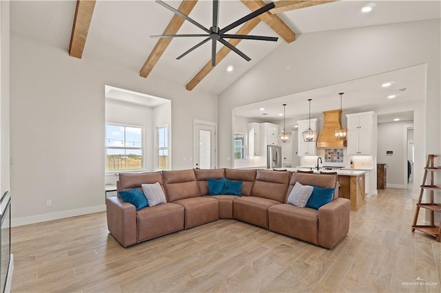 living room featuring ceiling fan, sink, beamed ceiling, high vaulted ceiling, and light hardwood / wood-style floors