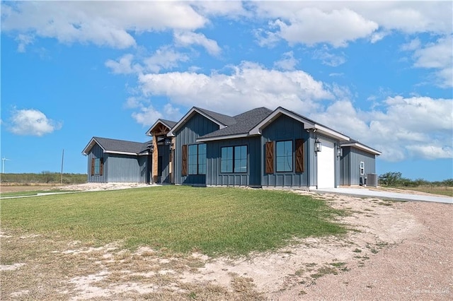 view of front of home featuring central AC unit, a garage, and a front yard