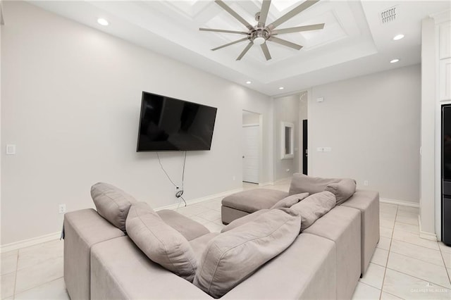 living room featuring ceiling fan, a tray ceiling, and light tile patterned floors