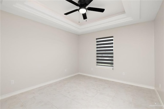 spare room with ceiling fan and a tray ceiling