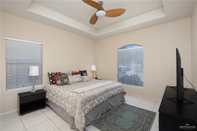 tiled bedroom featuring a raised ceiling and ceiling fan