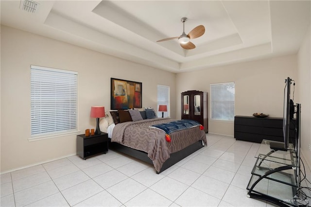 bedroom with light tile patterned floors, a tray ceiling, and ceiling fan