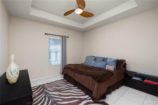 tiled bedroom featuring ceiling fan and a raised ceiling