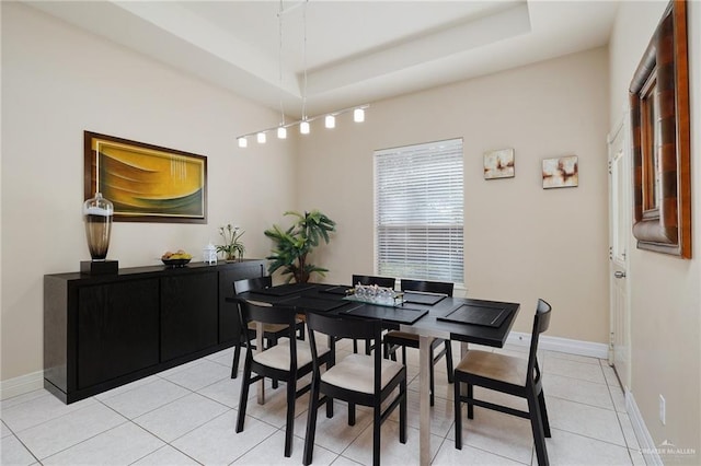 tiled dining space with a raised ceiling