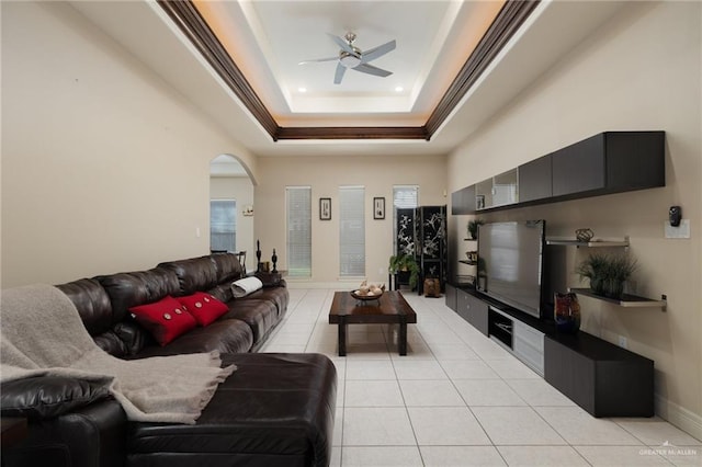 living room with light tile patterned floors, a tray ceiling, and ceiling fan