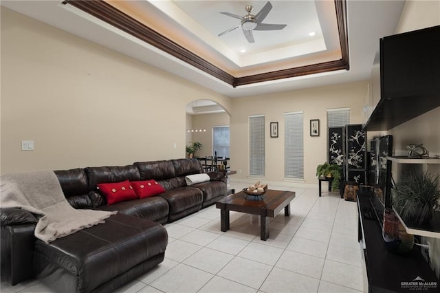 tiled living room featuring a raised ceiling and ceiling fan