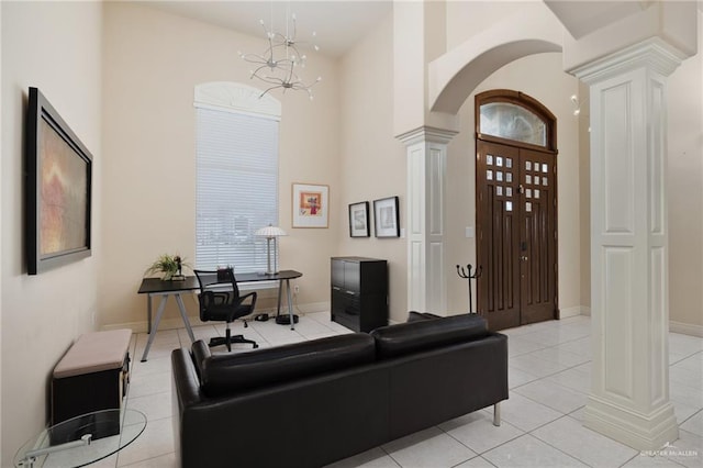 living room featuring ornate columns, light tile patterned flooring, a high ceiling, and an inviting chandelier