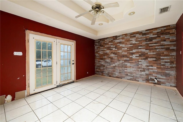 tiled spare room with ceiling fan and a raised ceiling