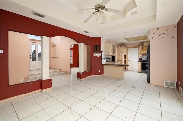 kitchen with a kitchen bar, light tile patterned floors, a tray ceiling, and ceiling fan