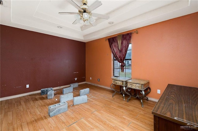 interior space featuring wood-type flooring, a tray ceiling, and ceiling fan