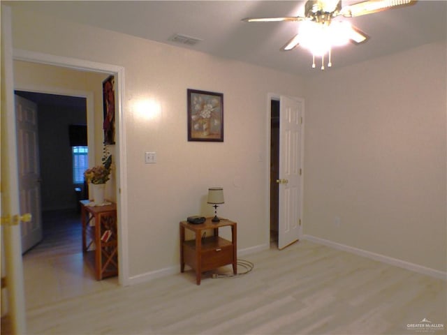 empty room with baseboards, a ceiling fan, light wood-style flooring, and visible vents