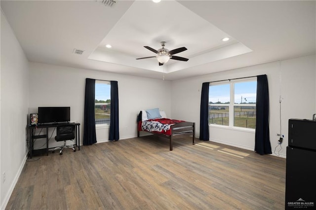 bedroom with a tray ceiling, ceiling fan, and hardwood / wood-style floors