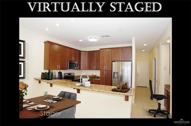 301 Houston St Unit 3303, Port Isabel, TX 78597 - kitchen featuring appliances with stainless steel finishes, a peninsula, light tile patterned floors, a kitchen breakfast bar, and brown cabinets