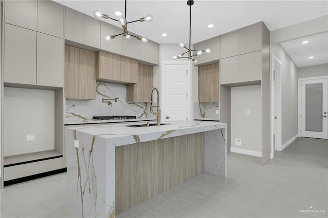 kitchen with tasteful backsplash, a chandelier, modern cabinets, gas stovetop, and a sink