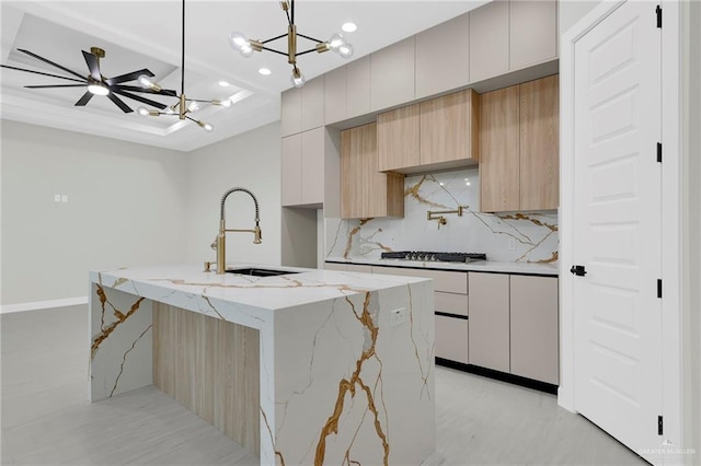 kitchen featuring tasteful backsplash, modern cabinets, a sink, a chandelier, and gas cooktop