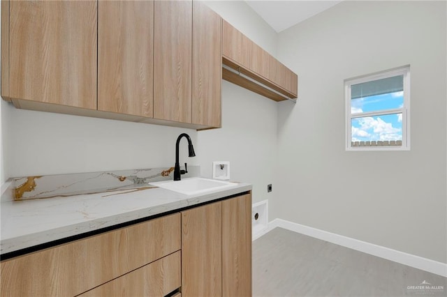 clothes washing area featuring a sink, baseboards, electric dryer hookup, and cabinet space