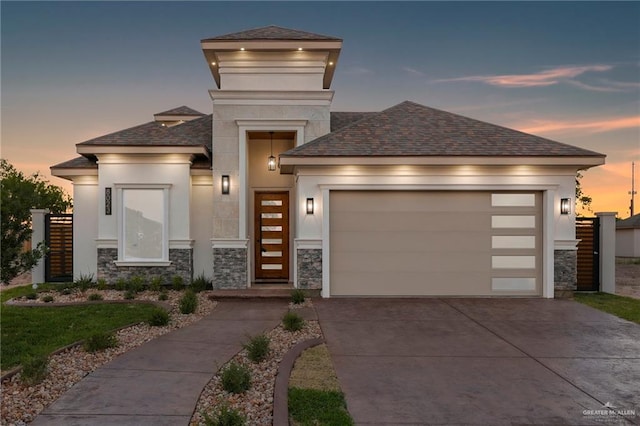 prairie-style house featuring concrete driveway, stucco siding, and stone siding