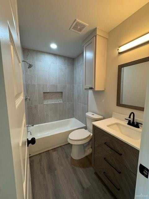 full bathroom featuring vanity, tiled shower / bath combo, wood-type flooring, and toilet