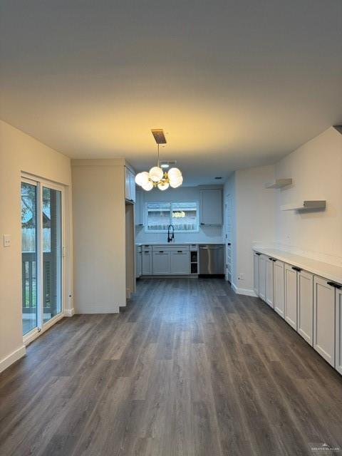 unfurnished living room featuring a notable chandelier, sink, and dark hardwood / wood-style floors