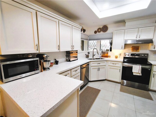2513 Sandpiper Ave, Mcallen, TX 78504 - kitchen with stainless steel appliances, a sink, under cabinet range hood, light countertops, and a peninsula