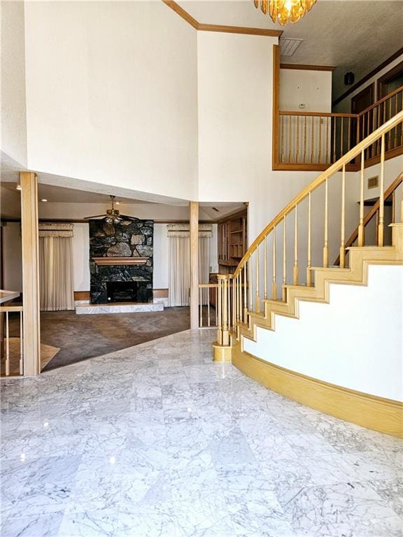 interior space with crown molding, a towering ceiling, and a fireplace