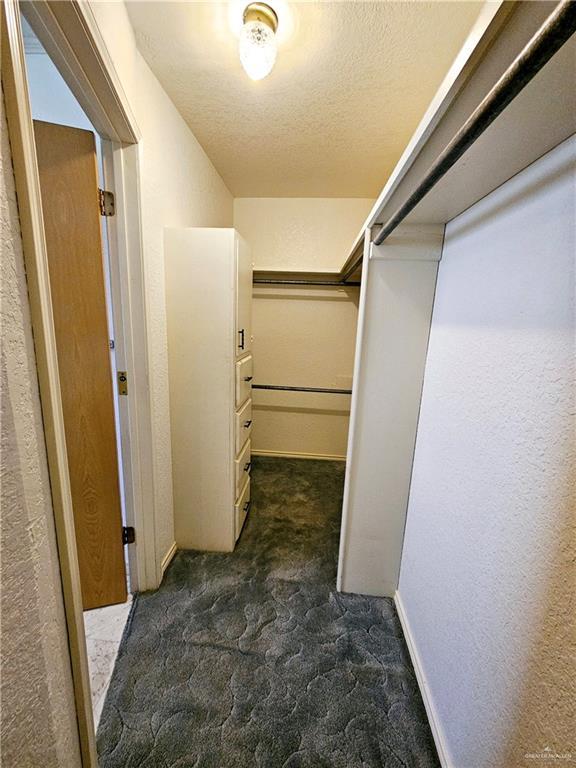 spacious closet featuring dark carpet