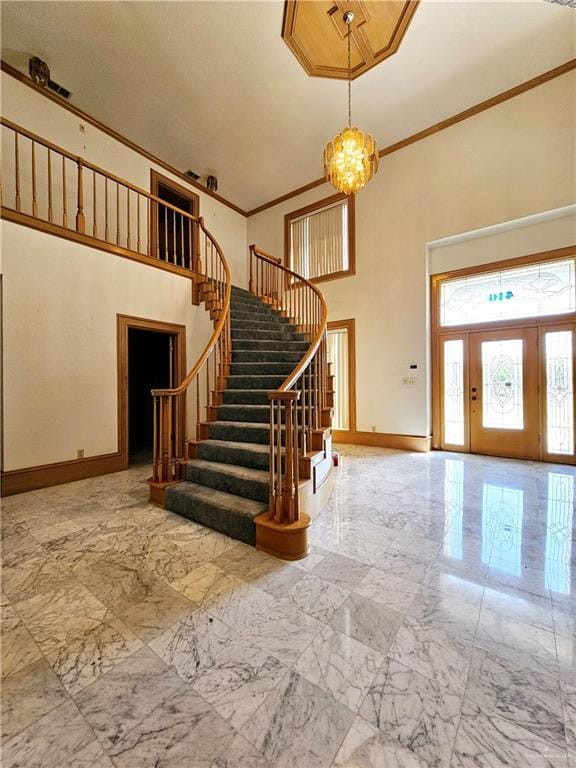 foyer entrance featuring crown molding and a towering ceiling