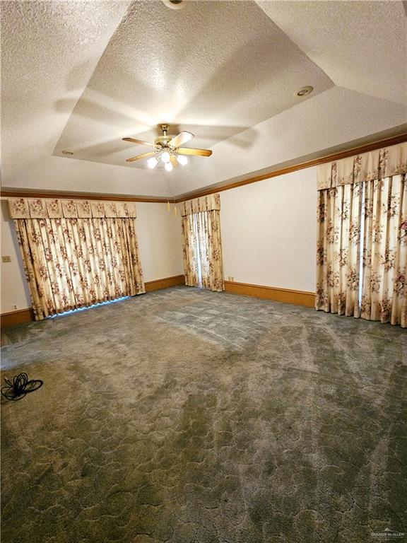 additional living space with ceiling fan, vaulted ceiling, a textured ceiling, and dark colored carpet