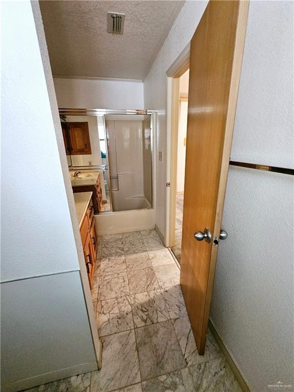 bathroom featuring vanity, shower / bath combination with glass door, and a textured ceiling