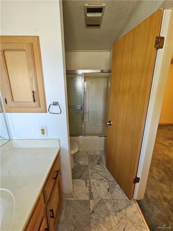 full bathroom with vanity, a textured ceiling, toilet, and combined bath / shower with glass door