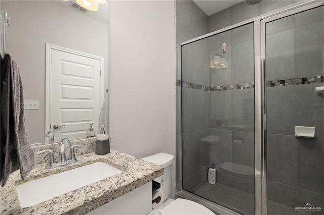 bathroom with vanity, toilet, and a shower with door