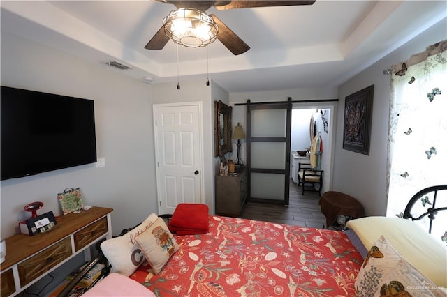 29082 Reynolds Dr, La Feria, TX 78559 - bedroom with a tray ceiling, a barn door, wood finished floors, and ceiling fan