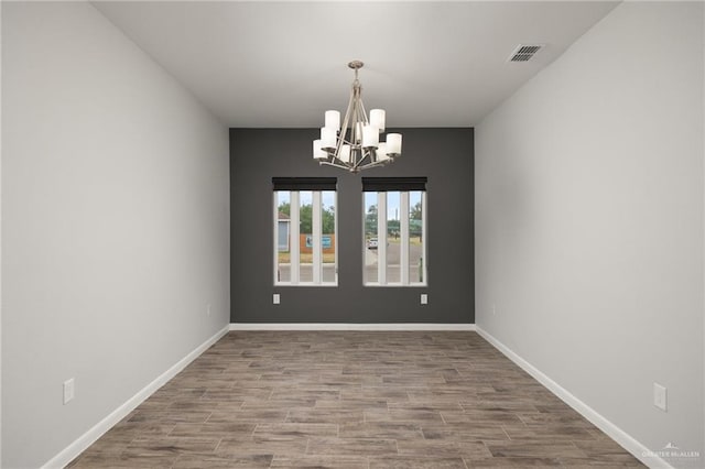 unfurnished dining area featuring a chandelier and wood-type flooring