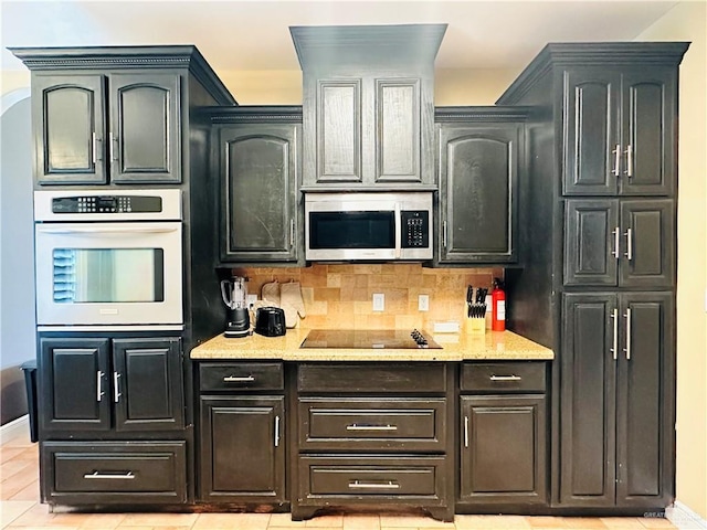 kitchen featuring decorative backsplash, light stone counters, light tile patterned floors, and appliances with stainless steel finishes