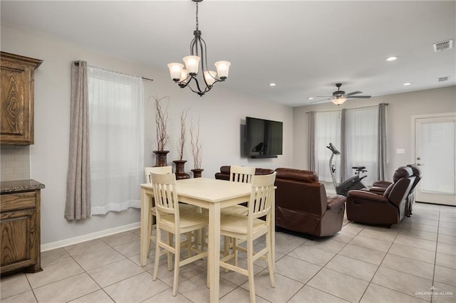 tiled dining space with ceiling fan with notable chandelier