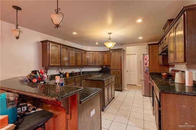 kitchen with a breakfast bar area, light tile patterned floors, decorative light fixtures, kitchen peninsula, and stainless steel appliances