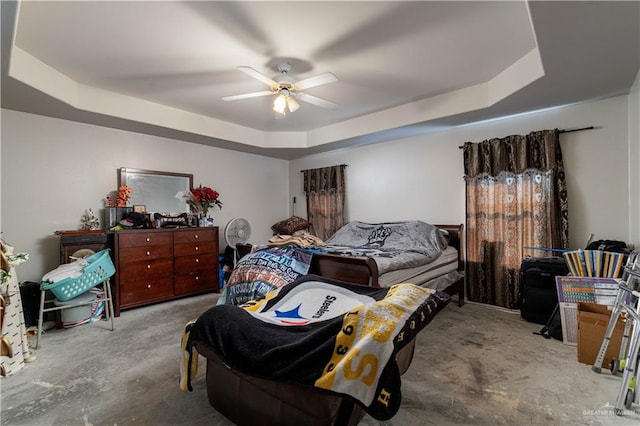 bedroom with ceiling fan, a raised ceiling, and concrete floors