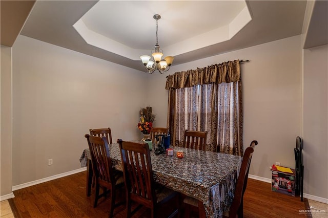 dining room featuring a tray ceiling, an inviting chandelier, and dark wood-type flooring