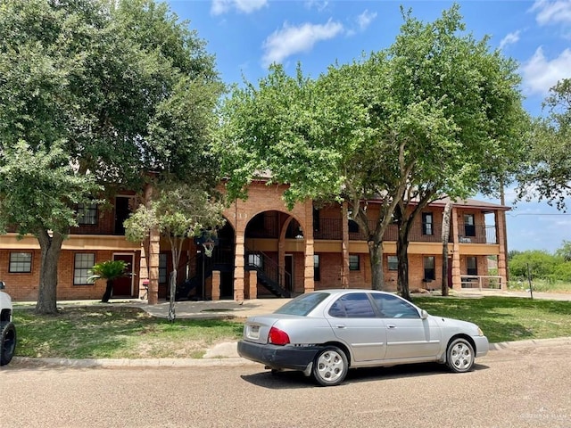 view of front of property with brick siding, a front lawn, and stairs