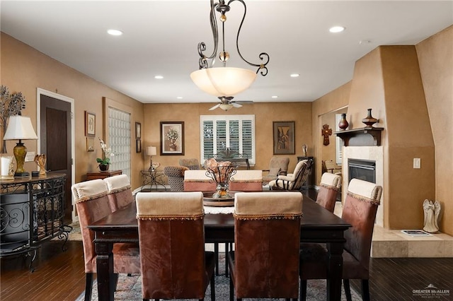 dining space featuring dark hardwood / wood-style floors, ceiling fan, and a tiled fireplace