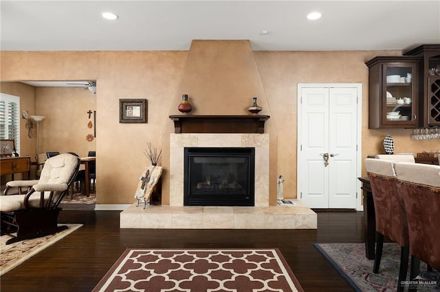 living room featuring dark wood-type flooring and a tiled fireplace