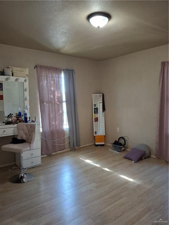 interior space with a textured ceiling, wood finished floors, and baseboards